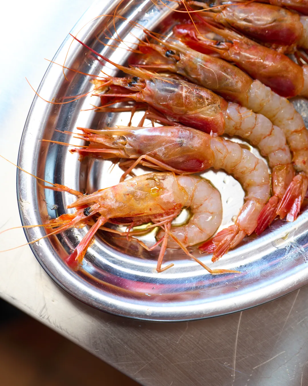 Gambas rojas frescas sobre bandeja de acero en la cocina